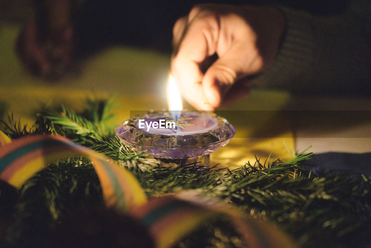 Close-up of hand holding lit candle