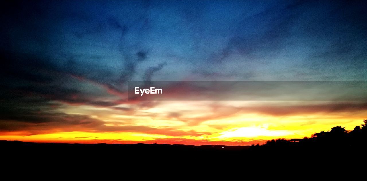 SILHOUETTE LANDSCAPE AGAINST DRAMATIC SKY DURING SUNSET