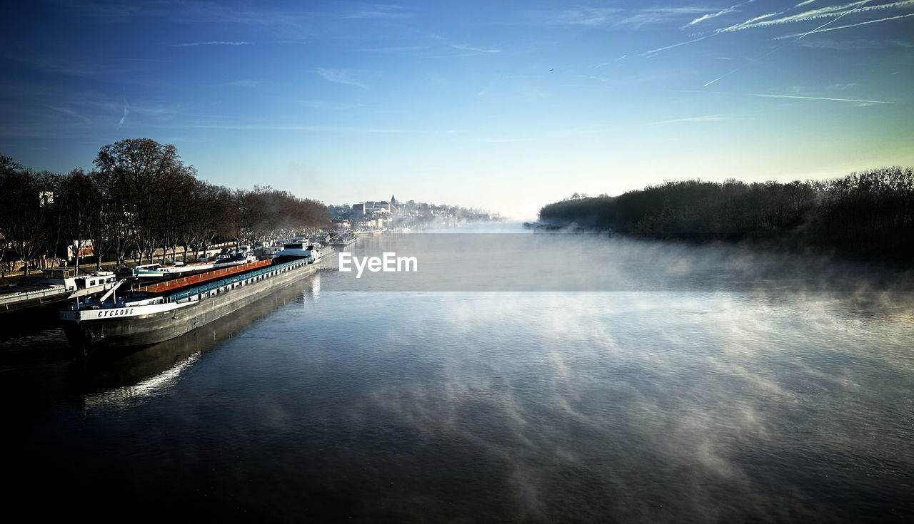 water, reflection, nautical vessel, sky, tree, nature, transportation, morning, scenics - nature, mode of transportation, beauty in nature, plant, sunlight, river, cloud, dusk, wave, travel, boat, tranquility, forest, landscape, outdoors, environment, travel destinations, light, land, no people, tranquil scene, blue, day, motion, watercraft, body of water, vehicle, non-urban scene