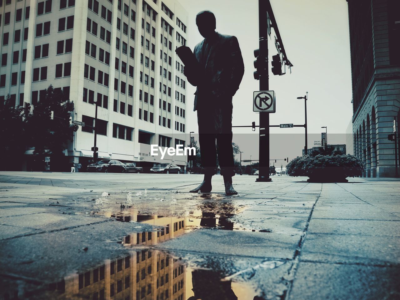 REAR VIEW OF MAN STANDING IN PUDDLE
