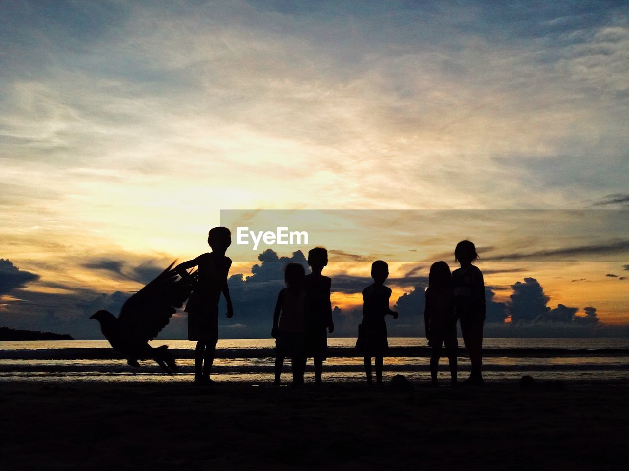 SILHOUETTE MEN STANDING ON BEACH AGAINST SKY DURING SUNSET