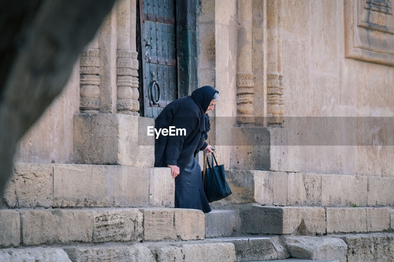 WOMAN WALKING ON STONE WALL