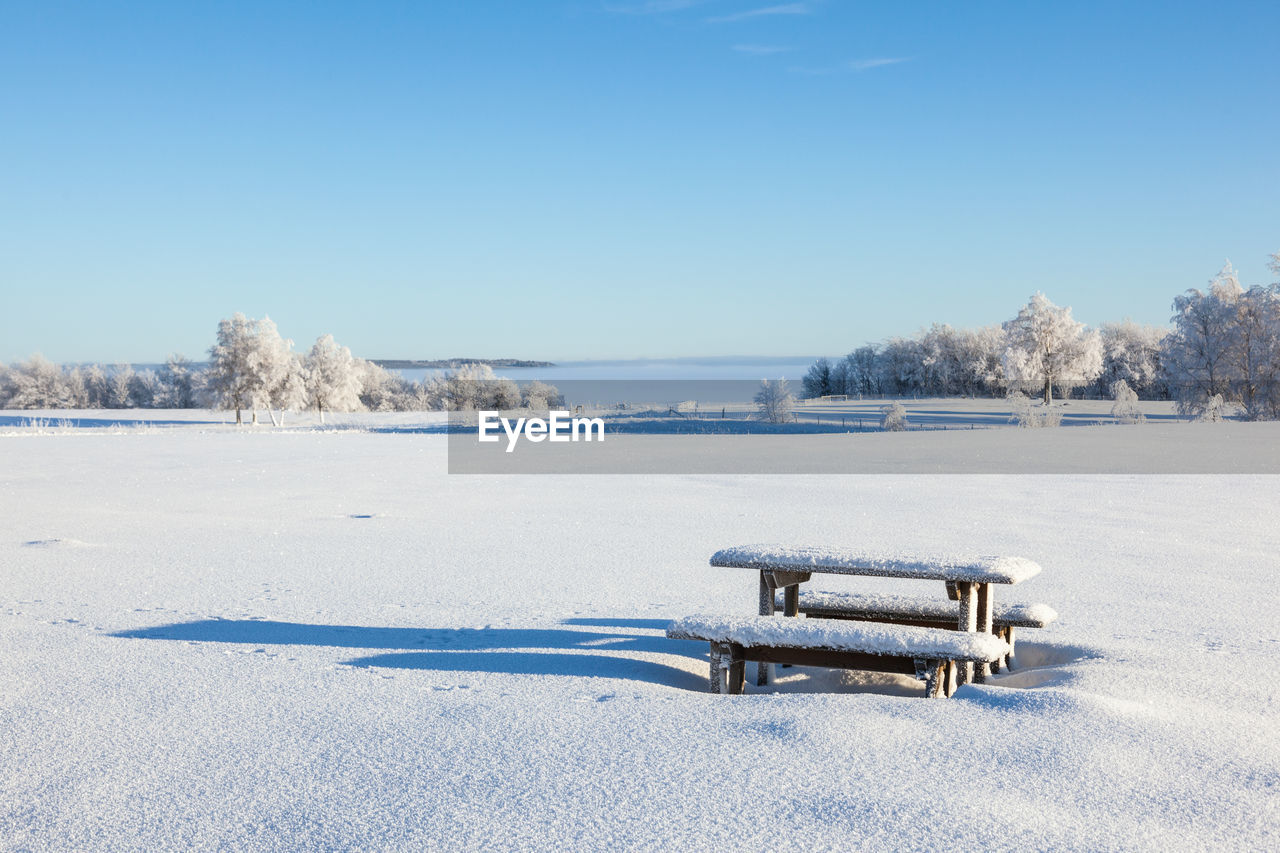 Scenic view of snow covered field against clear blue sky