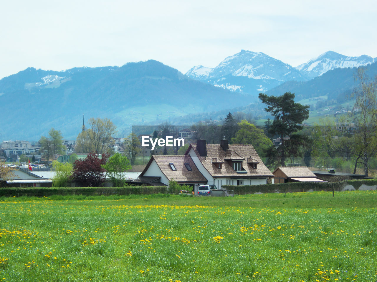 Houses on field by mountains against sky