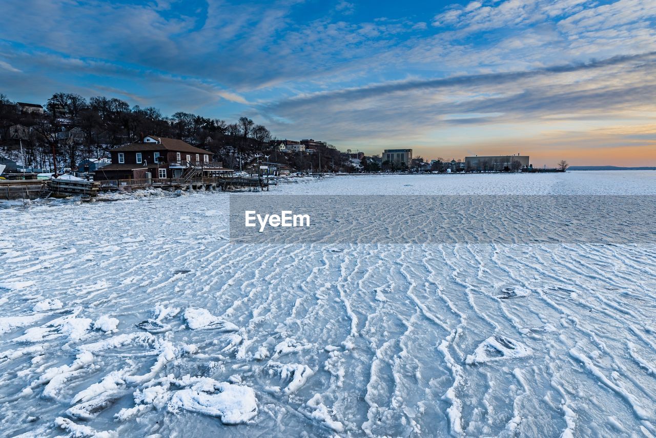 Scenic view of frozen landscape against sky during winter