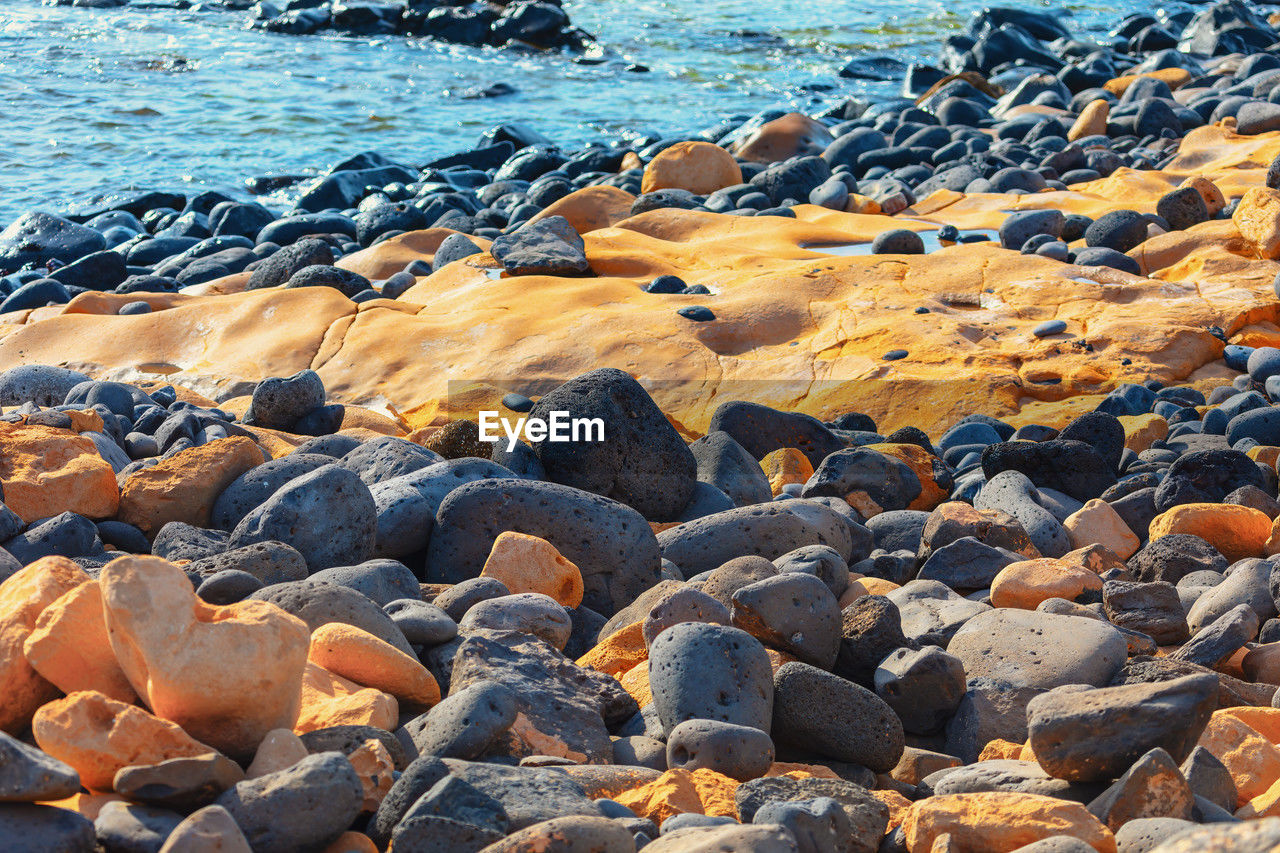 water, sea, beach, rock, land, shore, nature, beauty in nature, coast, no people, day, tranquility, scenics - nature, sunlight, stone, pebble, tranquil scene, outdoors, abundance, non-urban scene, ocean, wave, geology, idyllic