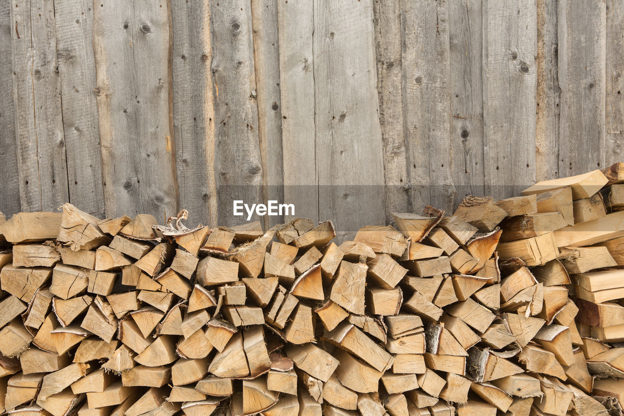 STACK OF LOGS AGAINST STONE WALL