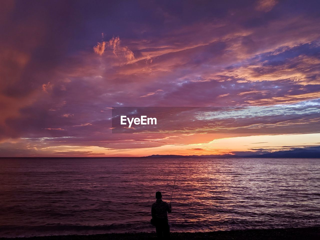 SILHOUETTE OF MAN LOOKING AT SEA AGAINST SKY