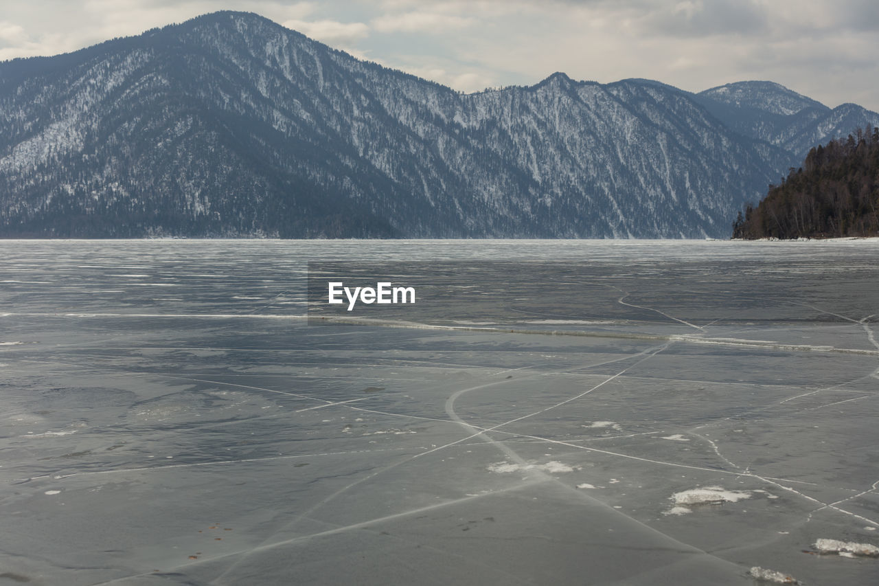 View of beautiful drawings on ice from cracks on the surface of lake teletskoye in winter, russia