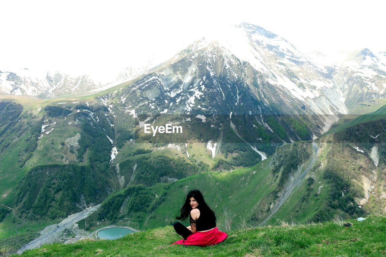 Portrait of woman sitting against mountain