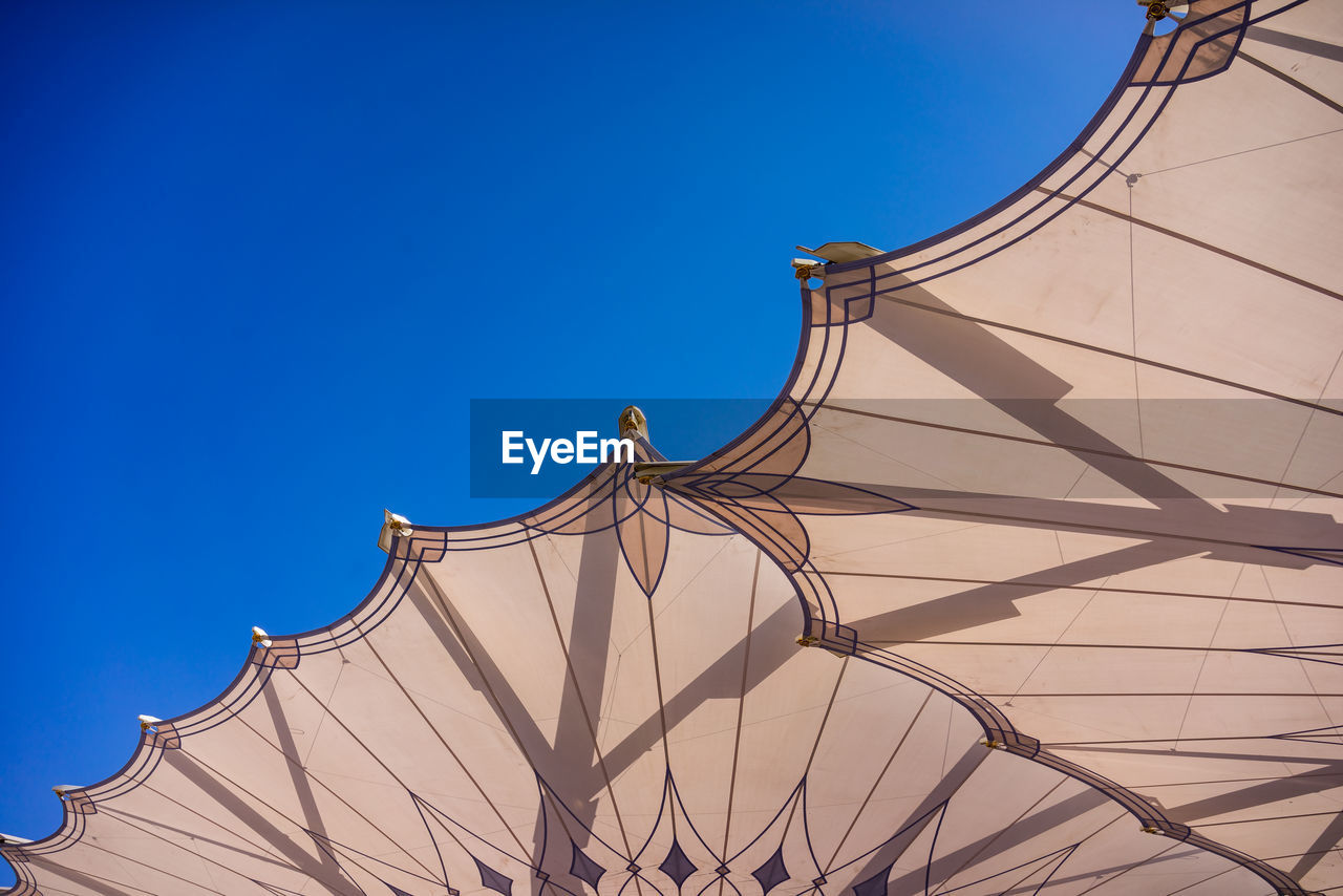 Directly below shot of parasols against clear blue sky