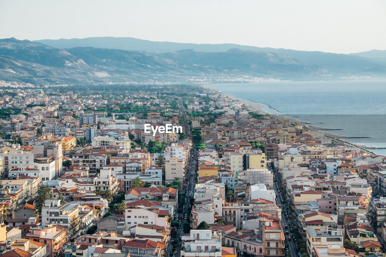 High angle view of townscape by sea against sky