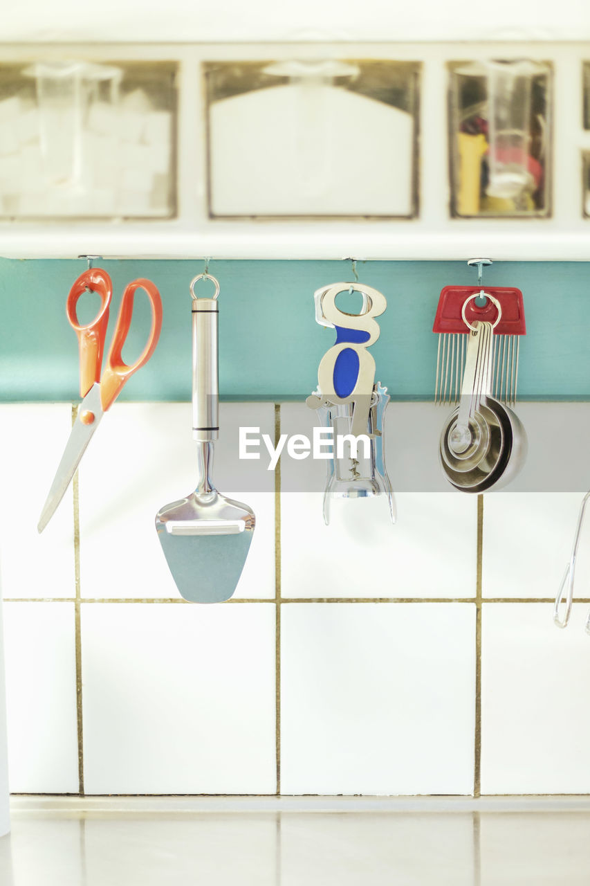 Kitchen equipment hanging on cabinet against tiled wall