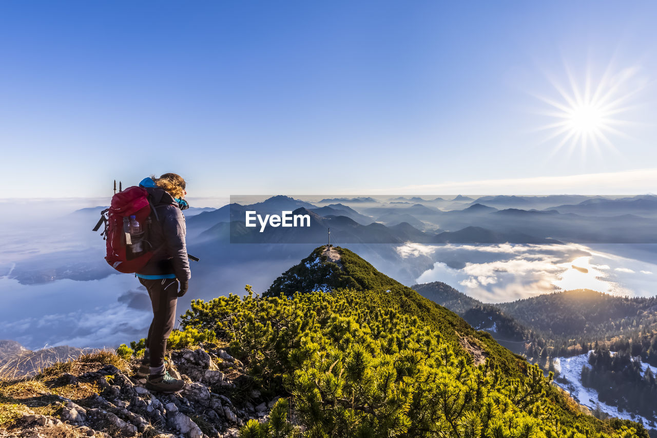Germany, bavaria, female hiker admiring surrounding landscape from summit of herzogstand mountain
