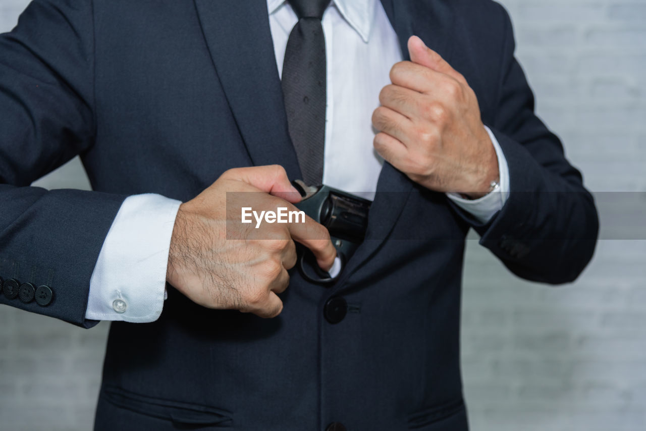 Midsection of businessman inserting handgun in blazer