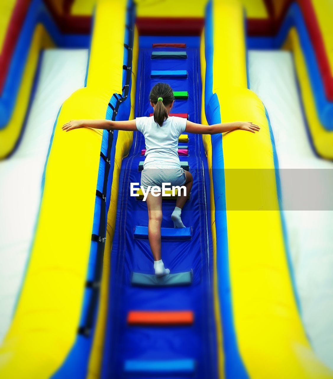 Rear view of girl playing on bouncy castle
