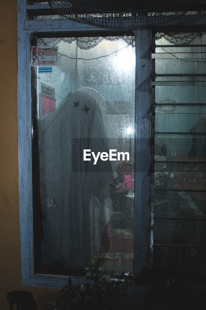 PEOPLE STANDING BY WINDOW OF BUILDING