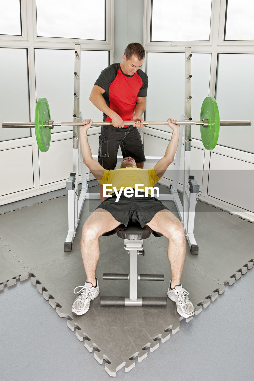 Personal trainer helping client in gym