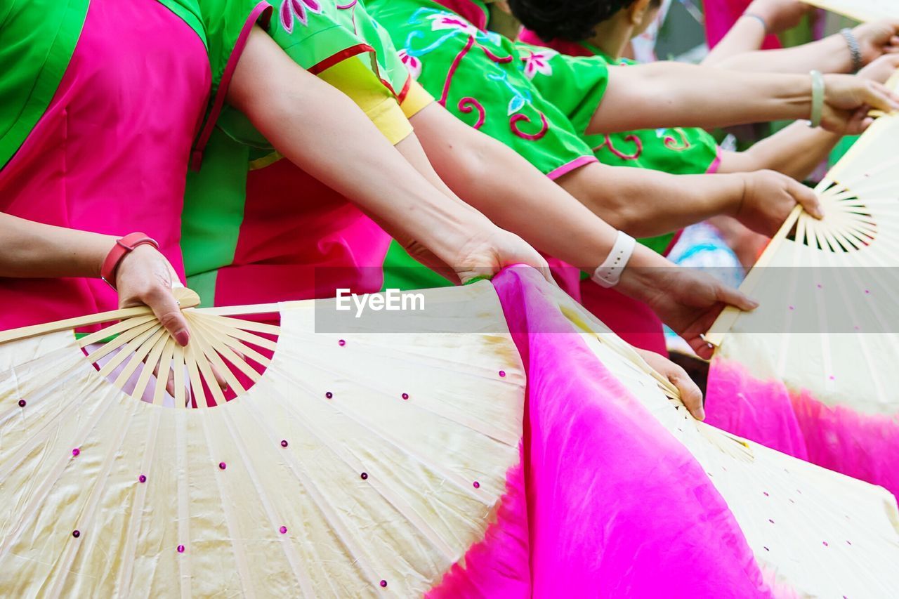 Women in traditional costume while dancing with folding fans at parade