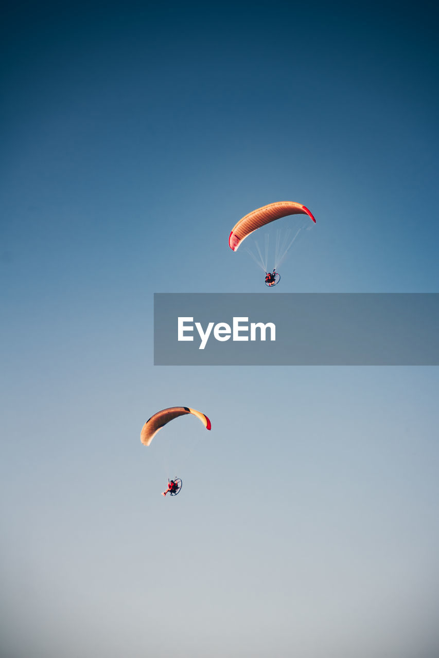 Low angle view of person paragliding against clear sky