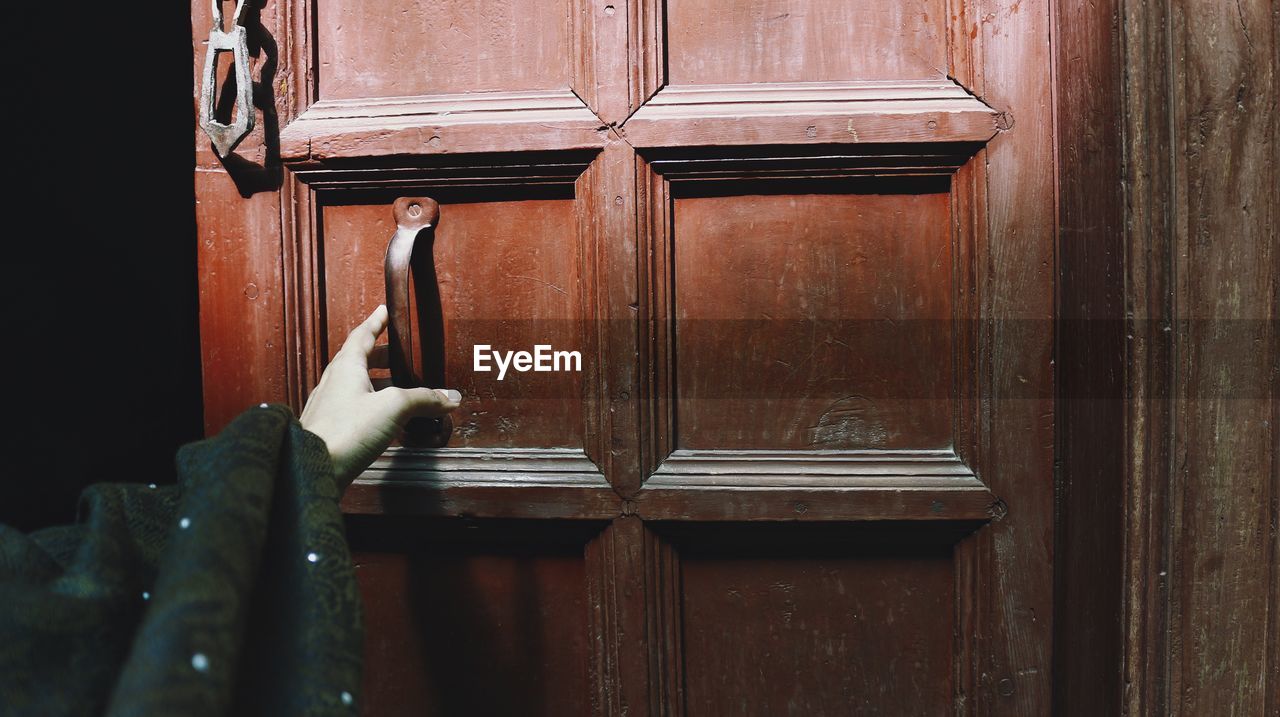 Close-up of a historic wooden door and a female hand