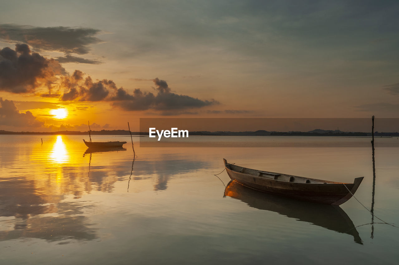 BOAT MOORED IN SEA DURING SUNSET