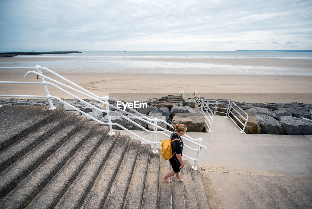 High angle view of woman moving down on steps against beach