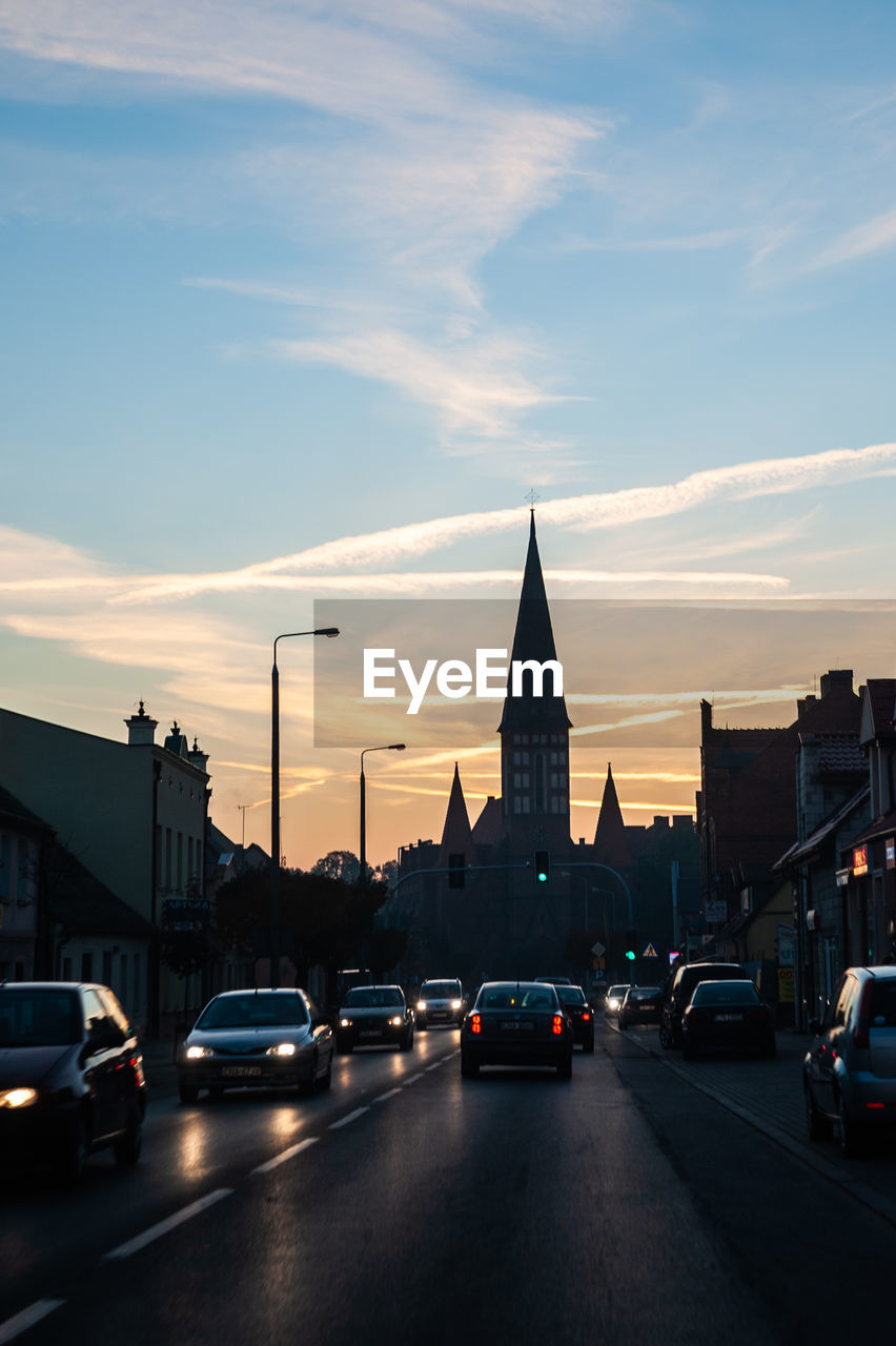 A street in the city. late afternoon, cars go with the lights on, even though the sky is bright