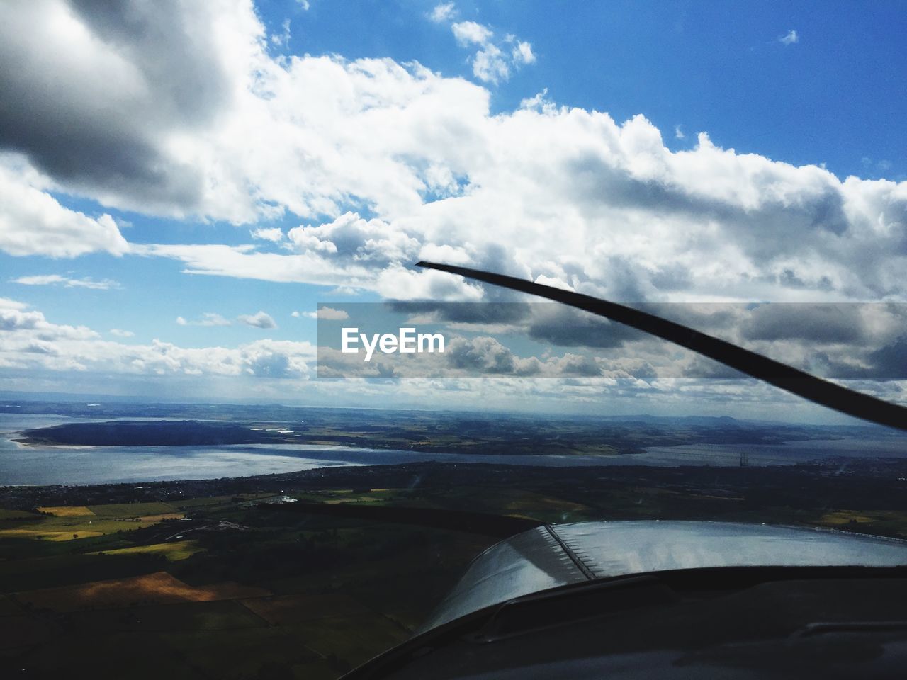 Cropped image of airplane flying over river and field