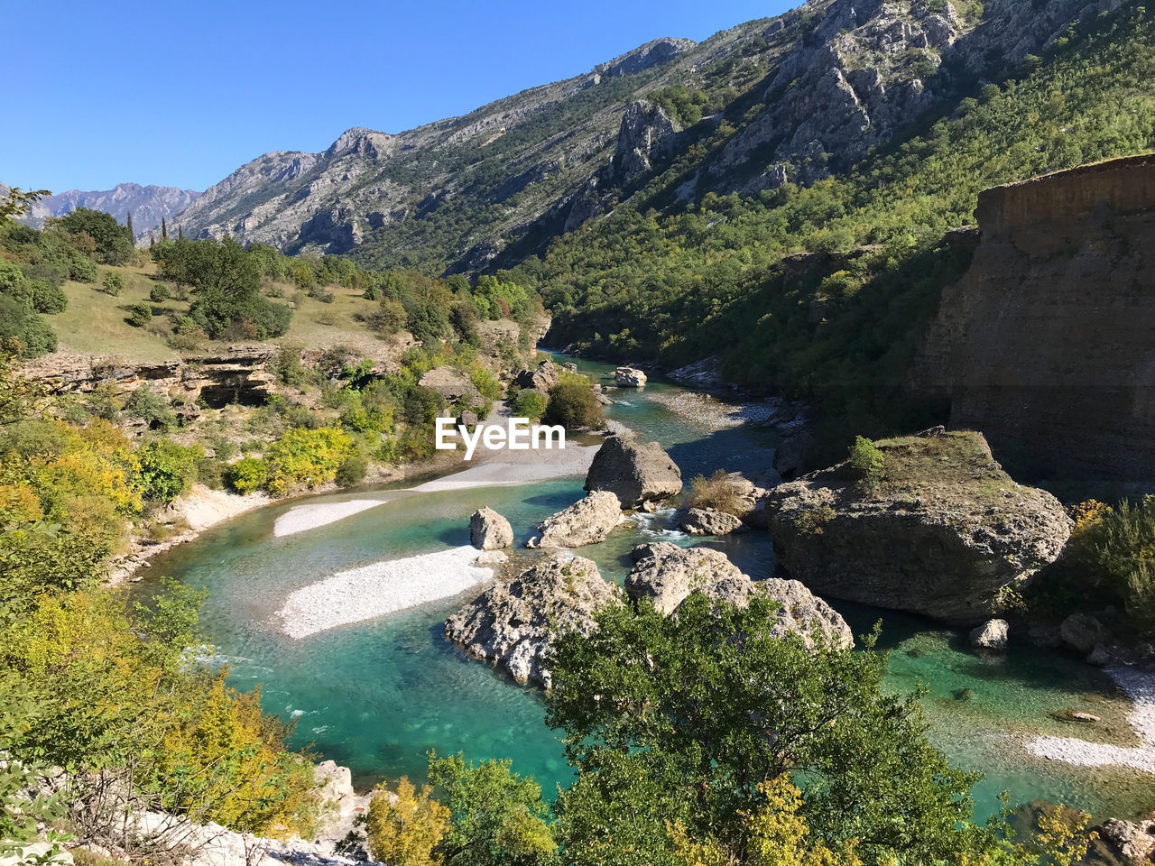 water, scenics - nature, mountain, nature, beauty in nature, plant, environment, landscape, tree, land, travel destinations, sky, rock, tranquility, travel, sunny, clear sky, tranquil scene, blue, non-urban scene, lake, no people, pinaceae, mountain range, sunlight, valley, tourism, day, pine tree, coniferous tree, outdoors, idyllic, wilderness, pine woodland, vacation, forest, summer, adventure, walking, leisure activity, reservoir, activity