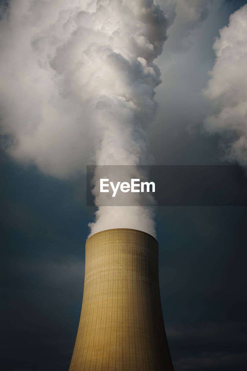 Low angle view of smoke stacks against sky