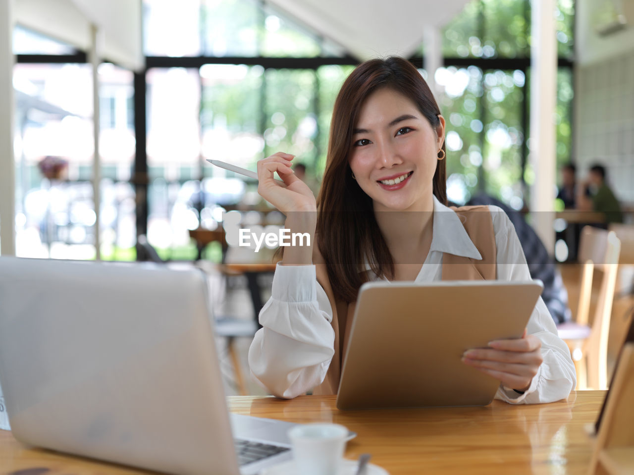 Portrait of smiling businesswoman using laptop sitting at cafe