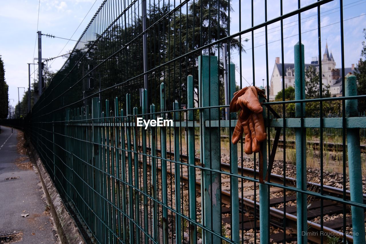 WOMAN STANDING BY FENCE AGAINST BUILDING