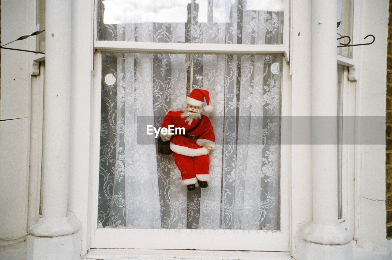 Santa claus doll hanging on window at home