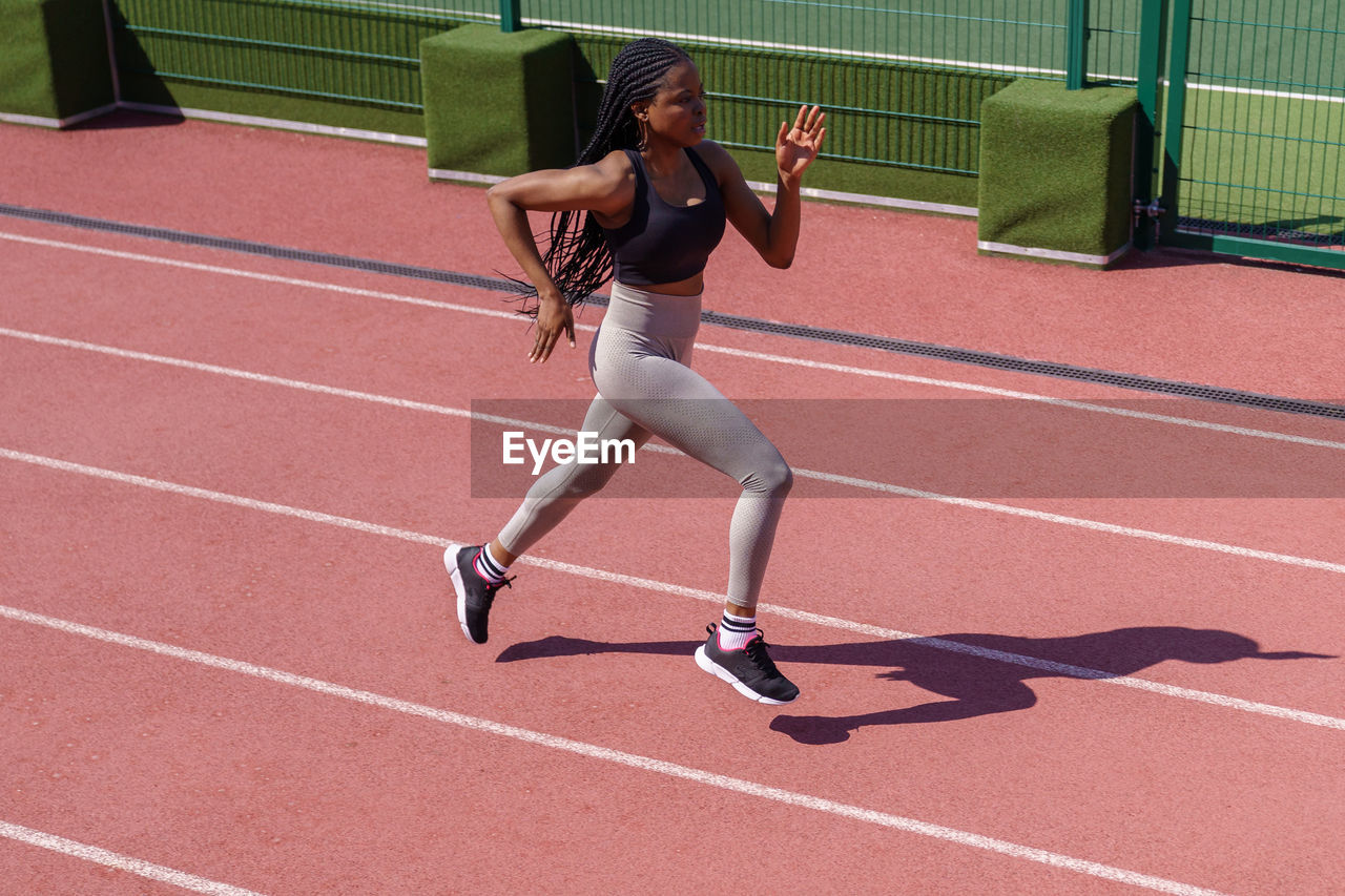 African woman athlete running on racetrack. sportive black female training jog on stadium sprinting