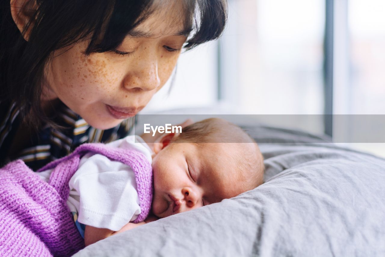 Close-up of mother by daughter sleeping on bed