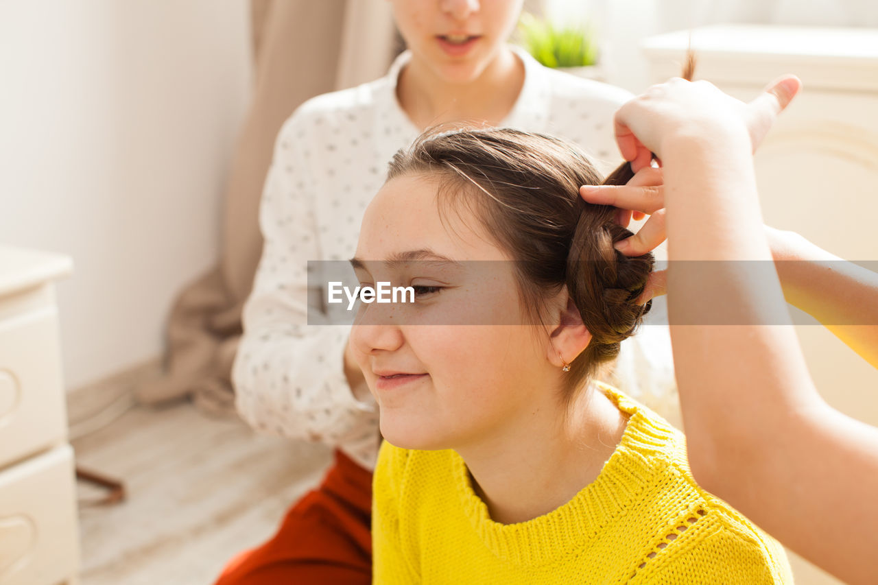 Sister making braids of sibling at home