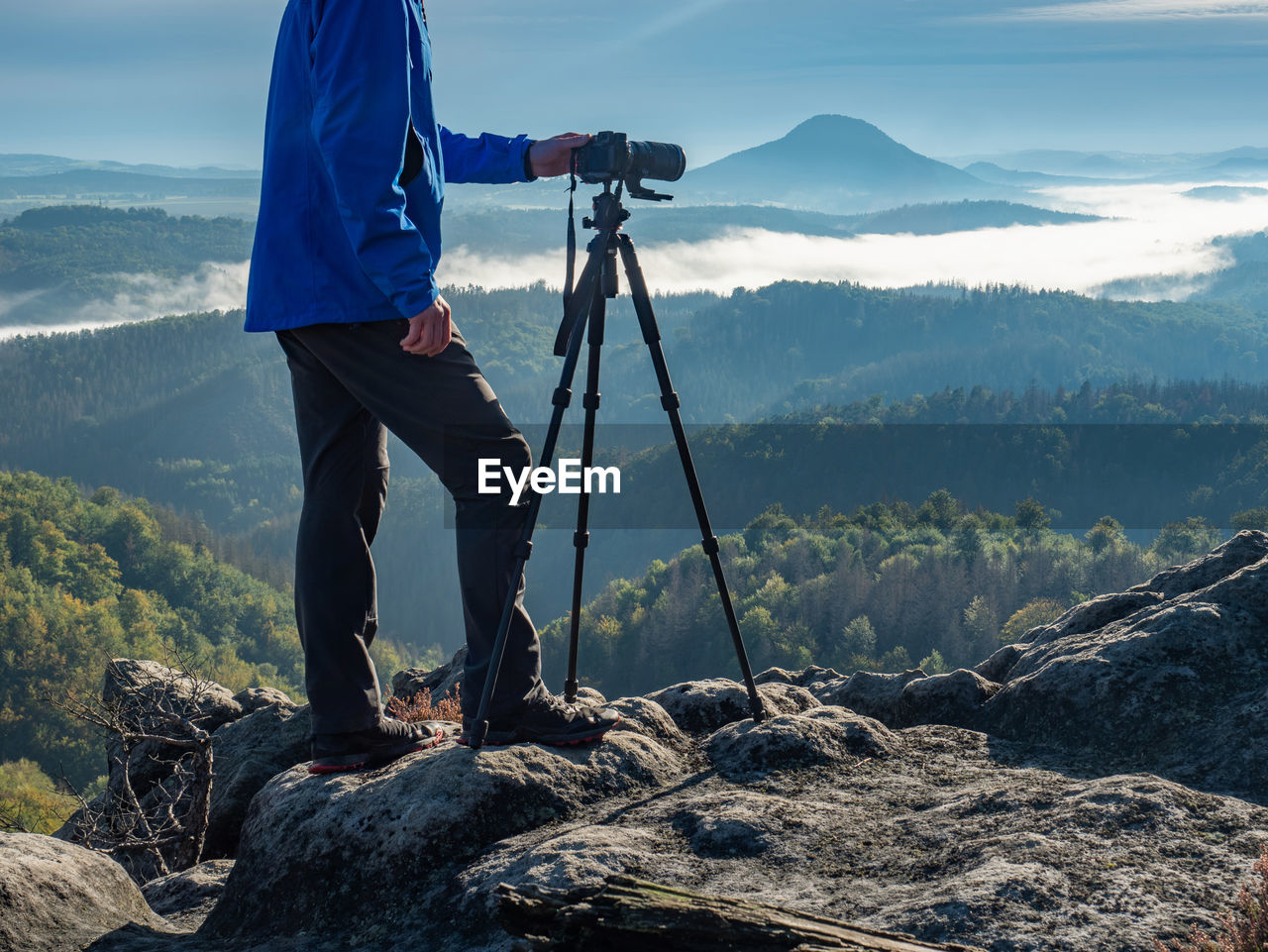 Outdoor travel photographer journalist holding dslr camera in mountain background. environment theme