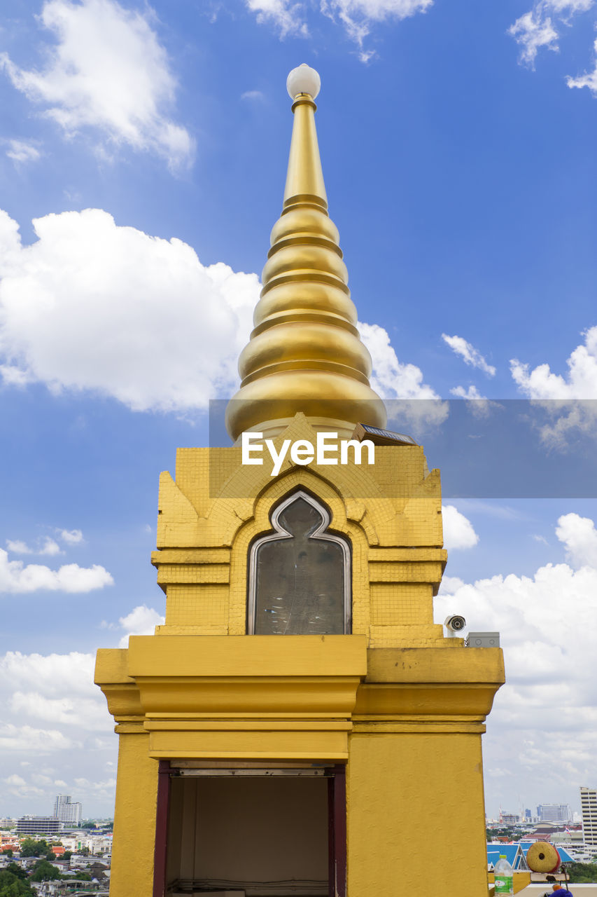 Low angle view of gold building against cloudy sky