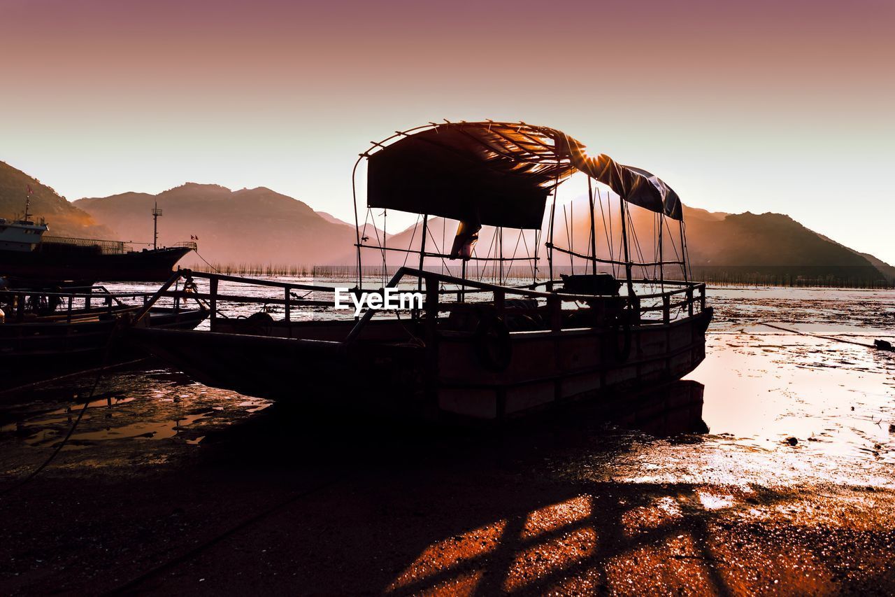 Silhouette boat on beach against sky during sunset