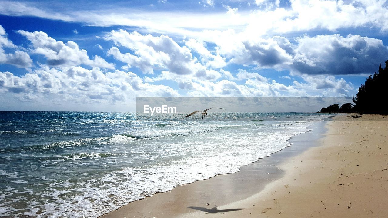 View of calm beach against cloudy sky