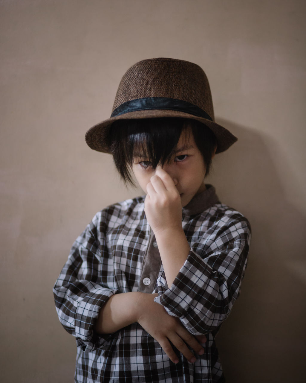 Portrait of boy wearing hat while standing against wall