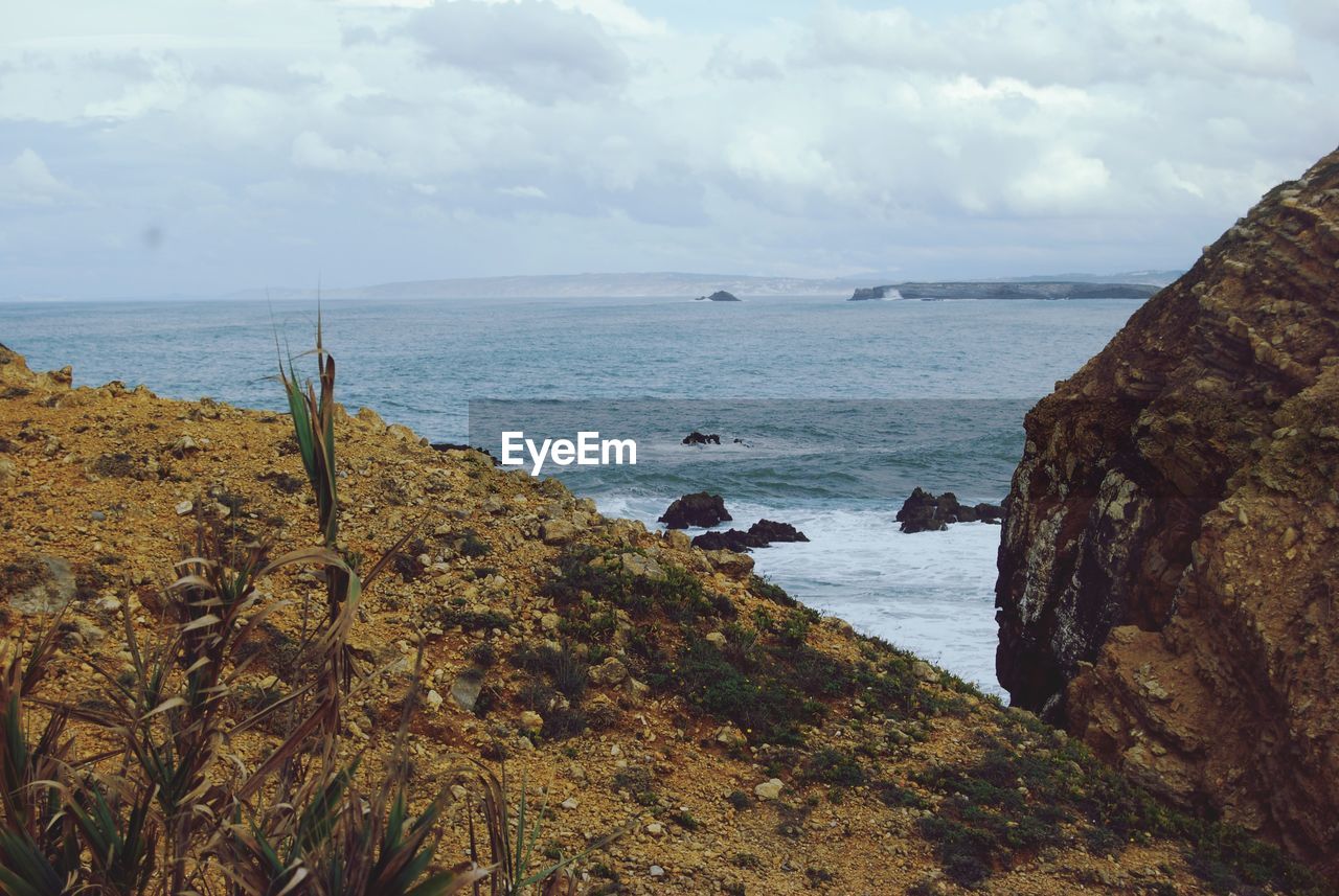 SCENIC VIEW OF ROCKS ON BEACH AGAINST SKY