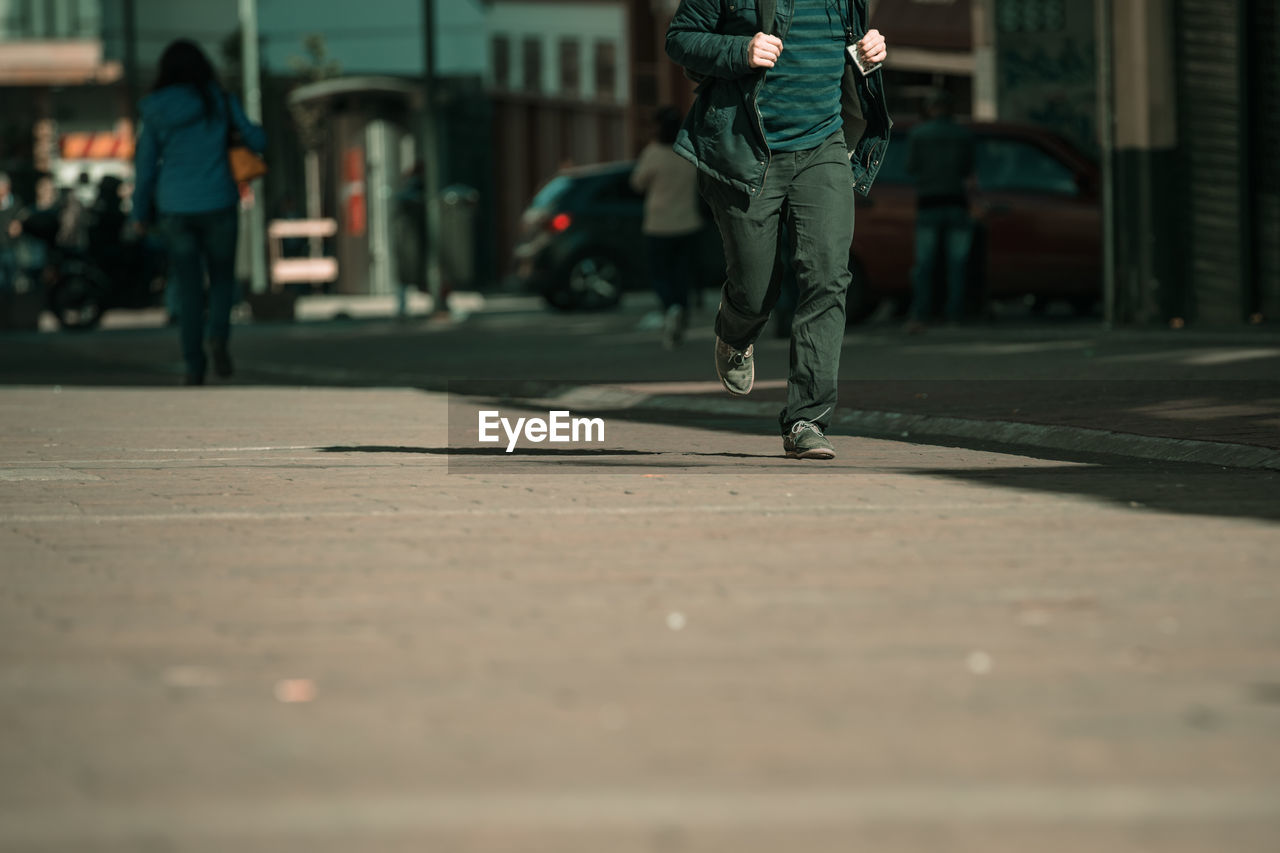 Low section of man walking on street in city