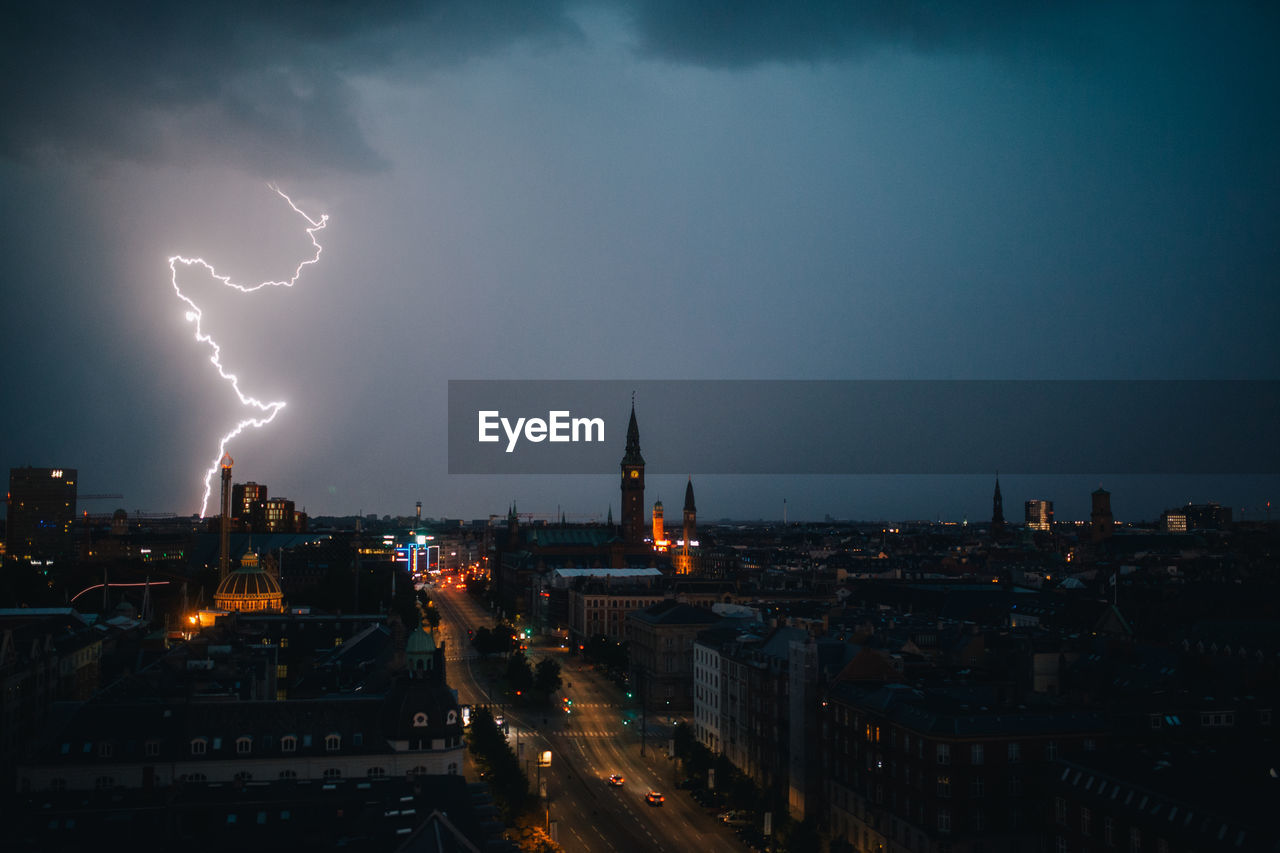 Lightning over cityscape against sky at night