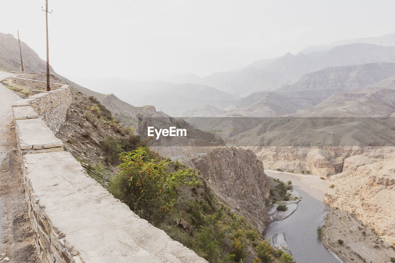 Layers of rocky mountains and hills in the morning haze, bend of a river in a canyon, top view.