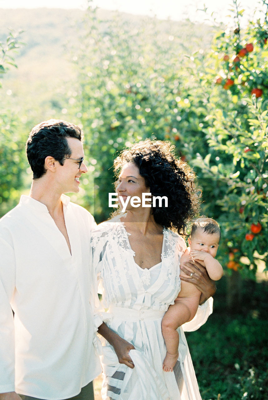 Cheerful parents with baby at farm