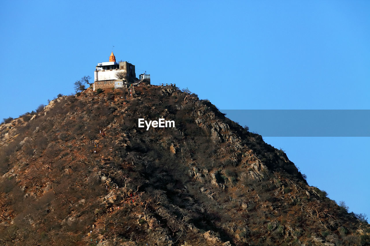 Low angle view of historic building on mountain against clear blue sky