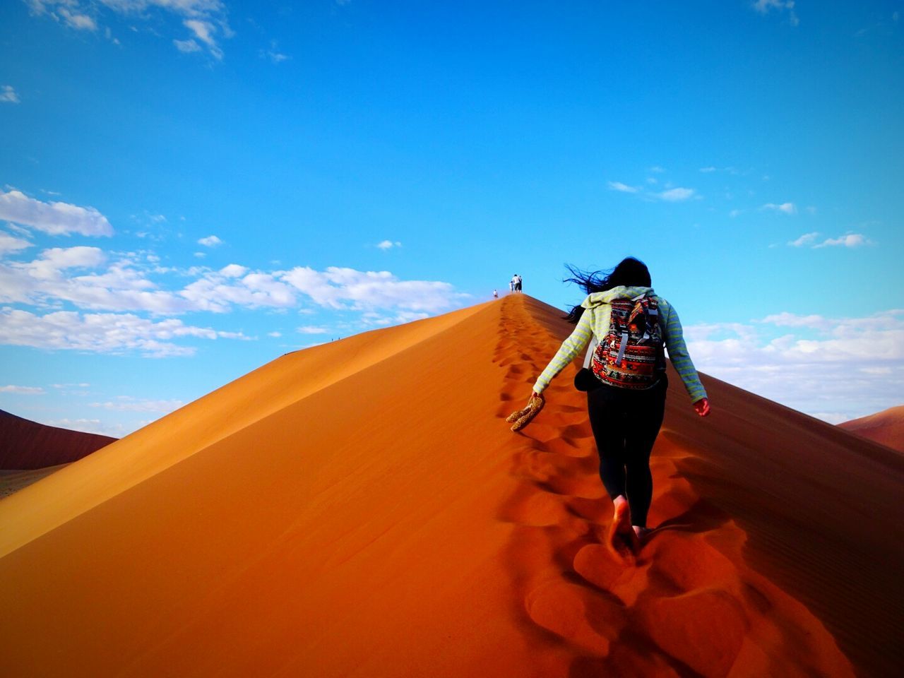 FULL LENGTH REAR VIEW OF MAN WALKING ON SAND DUNE