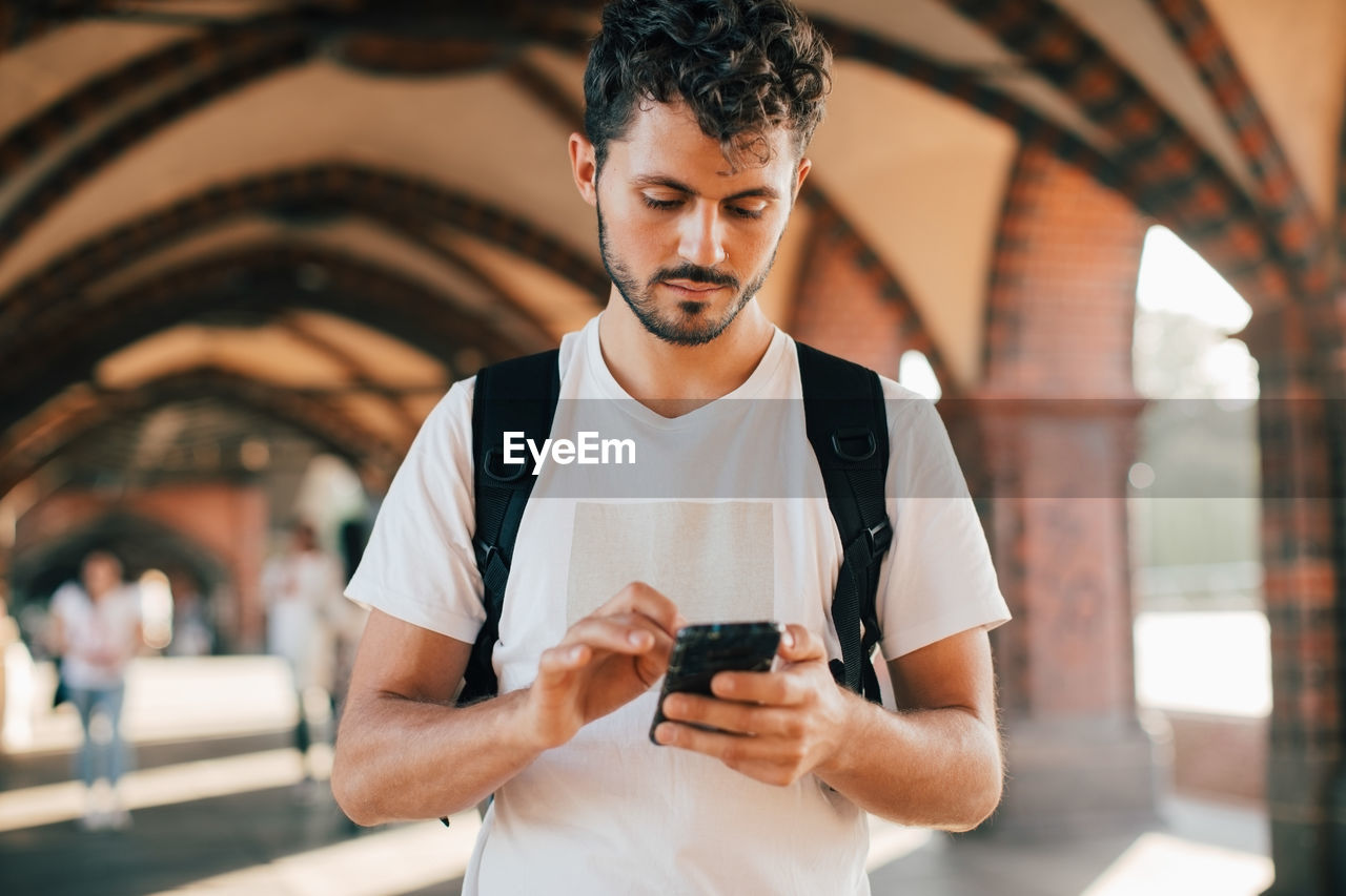 Young man using smart phone while standing on footpath